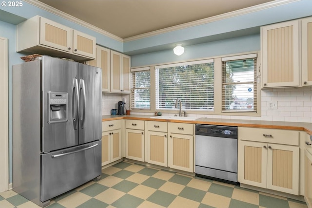 kitchen with appliances with stainless steel finishes, ornamental molding, sink, and backsplash