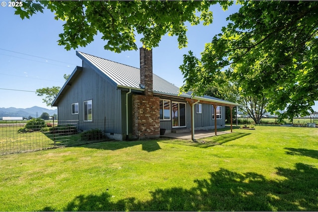 1770 Mccormick Loop Rd, Tillamook, OR 97141 - rear view of house featuring a standing seam roof, a chimney, a patio area, metal roof, and a mountain view