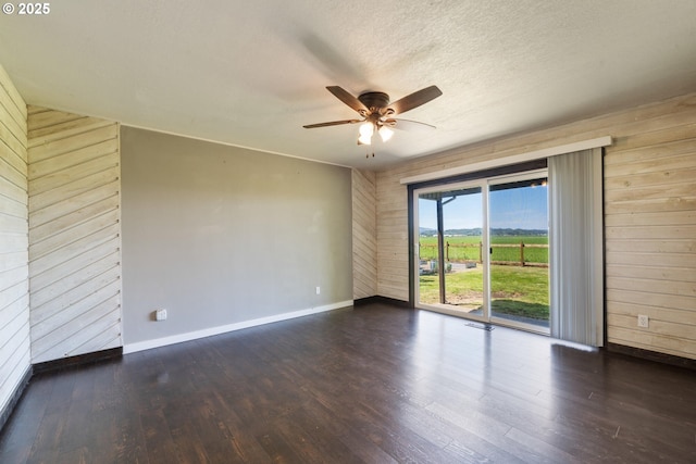 1770 Mccormick Loop Rd, Tillamook, OR 97141 - empty room with wood walls, ceiling fan, baseboards, wood finished floors, and a textured ceiling