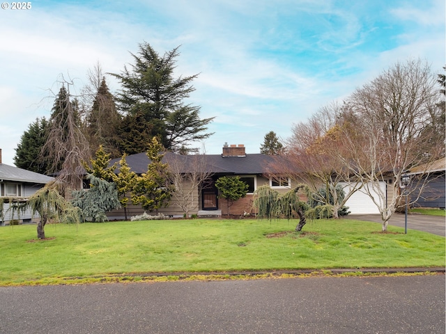 ranch-style home with a front yard, an attached garage, driveway, and a chimney