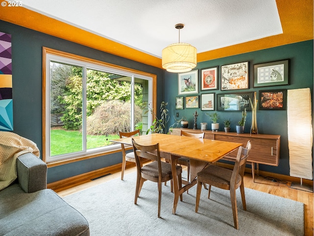 dining room featuring visible vents, baseboards, and wood finished floors