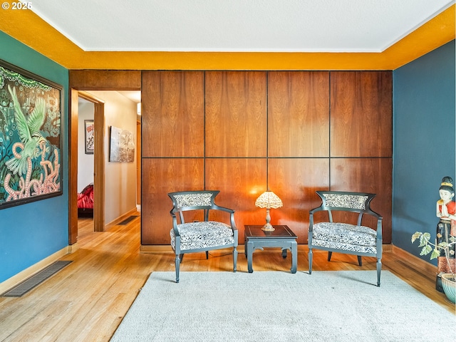 sitting room featuring visible vents, baseboards, and wood finished floors