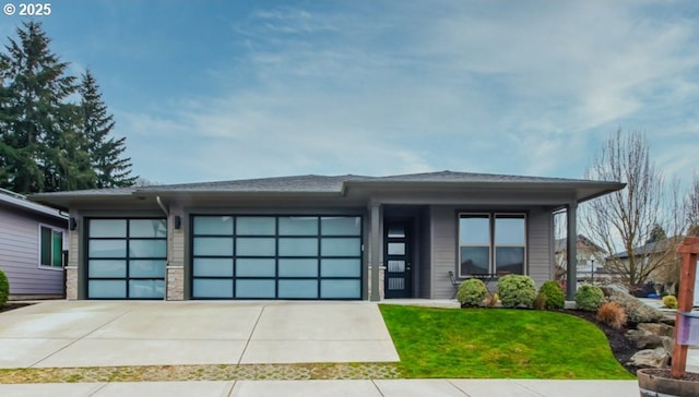 prairie-style house featuring driveway, a front lawn, and an attached garage