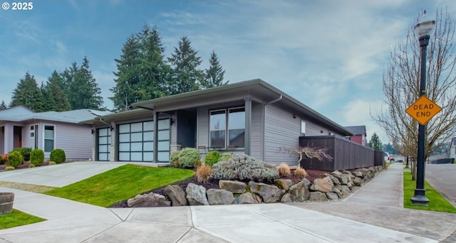 view of front of house with an attached garage, concrete driveway, and fence