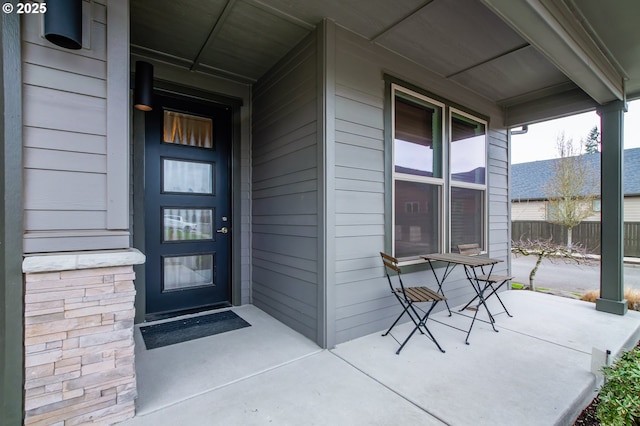 view of exterior entry with covered porch and fence