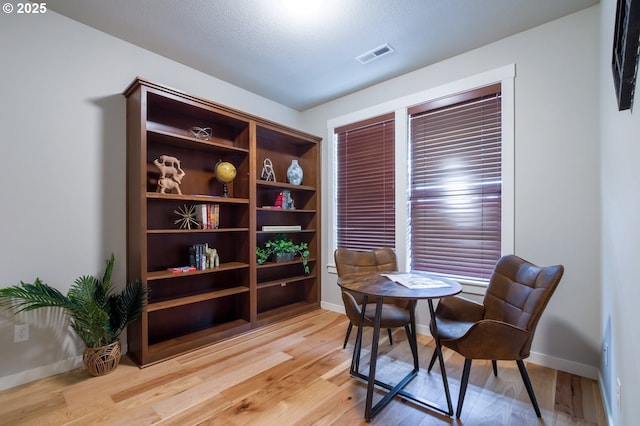 living area featuring visible vents, light wood-type flooring, and baseboards