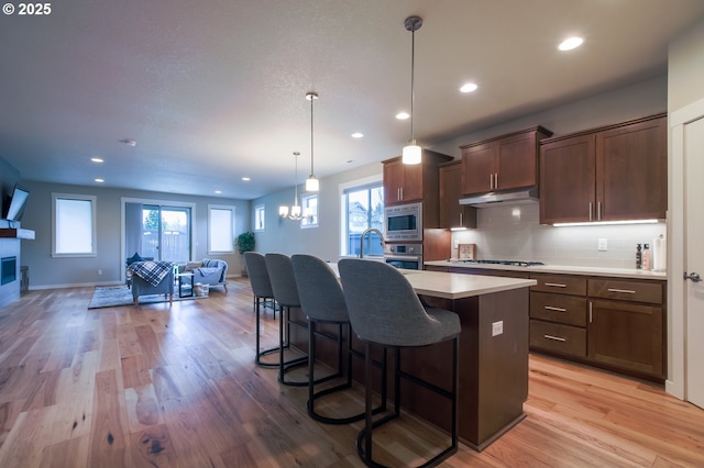 kitchen featuring backsplash, light wood-style floors, appliances with stainless steel finishes, and light countertops