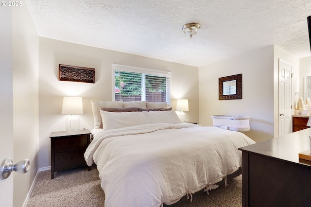 bedroom with carpet flooring, a textured ceiling, baseboards, and ensuite bathroom