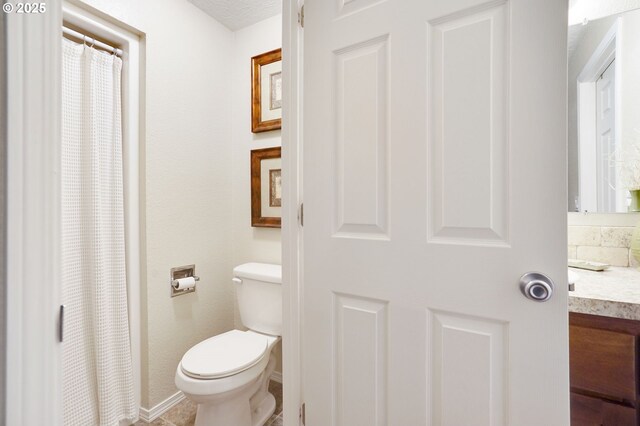 bathroom featuring toilet, vanity, and a shower with curtain