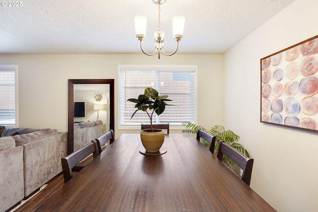 dining space with a chandelier, a textured ceiling, and wood finished floors