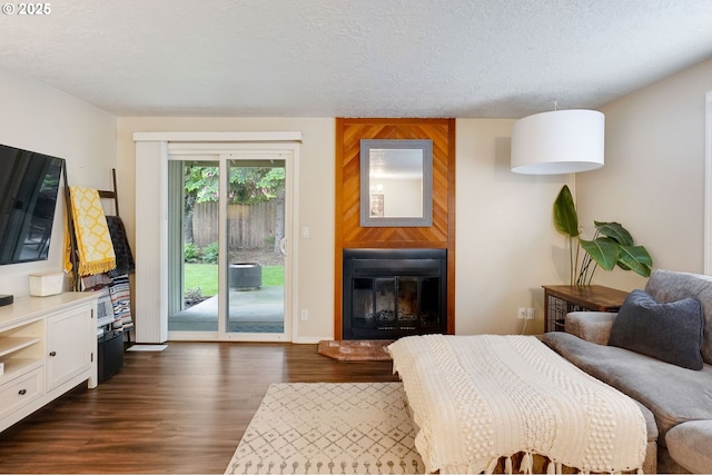 bedroom with access to exterior, a fireplace, dark wood finished floors, and a textured ceiling