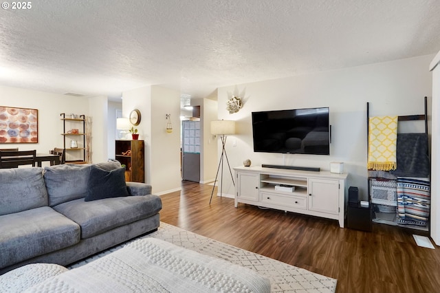living room featuring dark wood-style floors, a textured ceiling, and baseboards