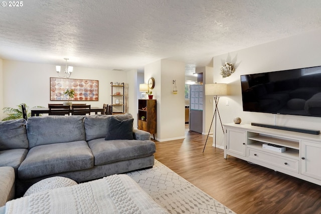 living area featuring dark wood finished floors, a textured ceiling, a chandelier, and baseboards
