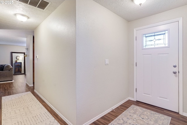 foyer with dark wood-style floors, a textured ceiling, and baseboards
