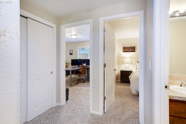 corridor featuring a sink, light colored carpet, and an office area