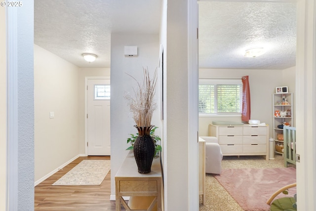 hallway featuring a textured ceiling, wood finished floors, and baseboards