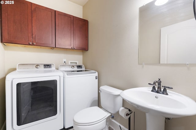 half bathroom with independent washer and dryer, a sink, and toilet