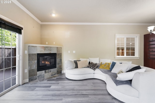 living area with crown molding, a tile fireplace, and wood finished floors