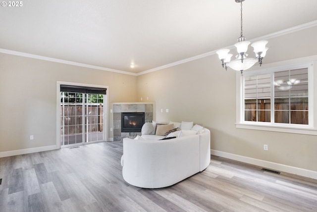 living room with a chandelier, a fireplace, wood finished floors, baseboards, and ornamental molding