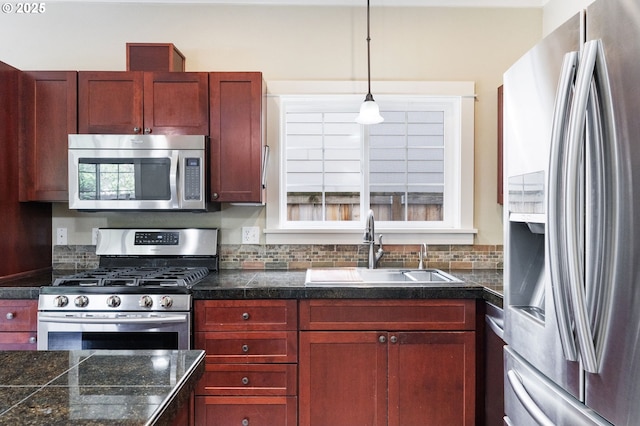 kitchen featuring appliances with stainless steel finishes, a sink, tile countertops, reddish brown cabinets, and backsplash
