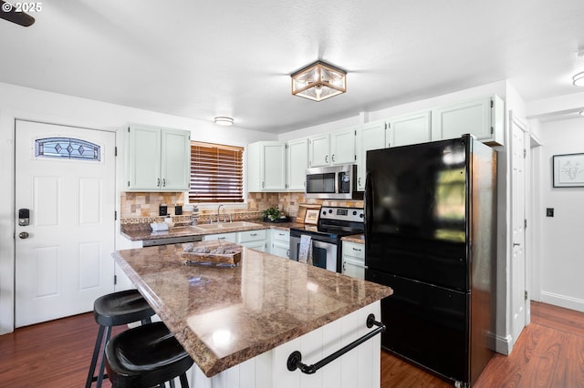 kitchen with sink, stainless steel appliances, white cabinets, a kitchen island, and decorative backsplash