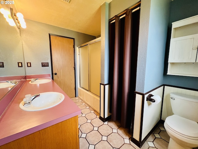 full bath featuring toilet, double vanity, and a sink