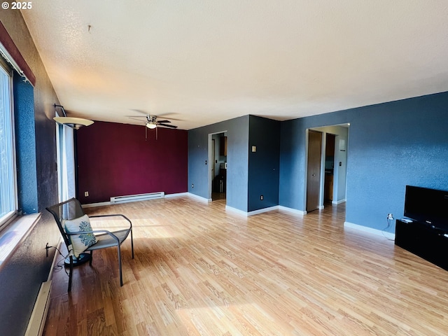 living area with a baseboard heating unit, baseboards, light wood finished floors, and a ceiling fan