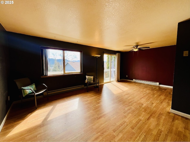 unfurnished room with a textured ceiling, a baseboard heating unit, wood finished floors, baseboards, and baseboard heating