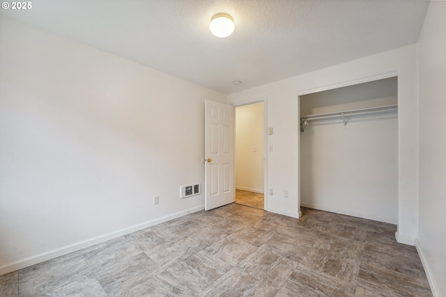 unfurnished bedroom featuring baseboards, a textured ceiling, visible vents, and a closet