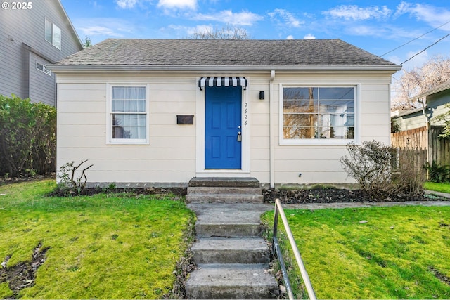 bungalow with a shingled roof, a front yard, fence, and entry steps