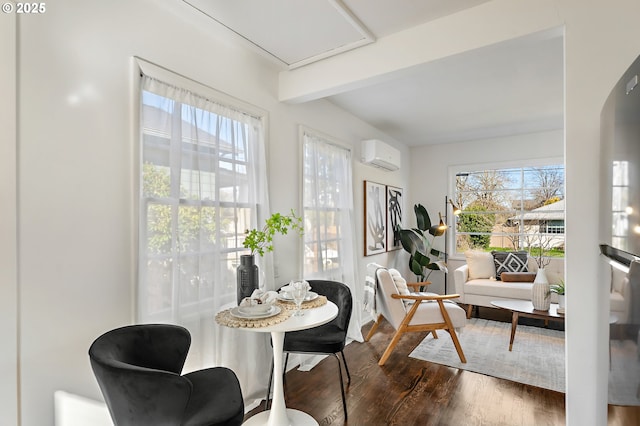 interior space featuring a wall unit AC, arched walkways, dark wood-style flooring, and beamed ceiling