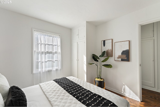 bedroom with dark wood-type flooring and baseboards