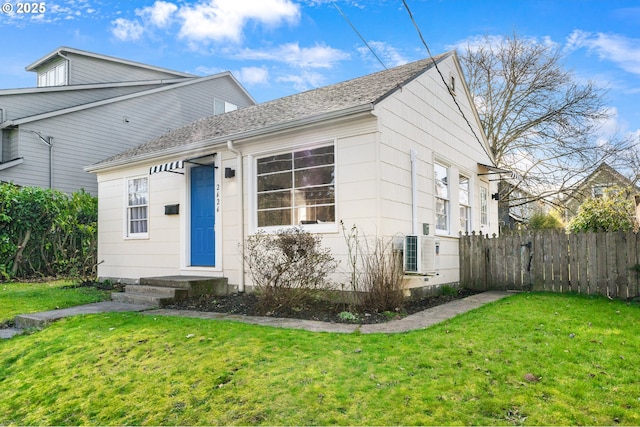 view of front of home featuring a front lawn, a shingled roof, and fence