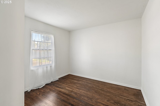 empty room with dark wood finished floors and baseboards