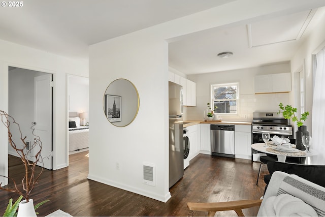 kitchen with dark wood-style floors, stainless steel appliances, light countertops, visible vents, and white cabinets