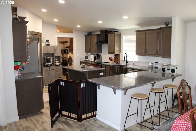 526 SE 15th St, Pendleton, OR 97801 - kitchen featuring wall chimney exhaust hood, white microwave, a kitchen breakfast bar, light wood-style floors, and recessed lighting