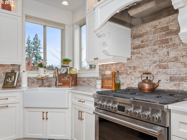 kitchen featuring white cabinetry, sink, high end stainless steel range, and tasteful backsplash