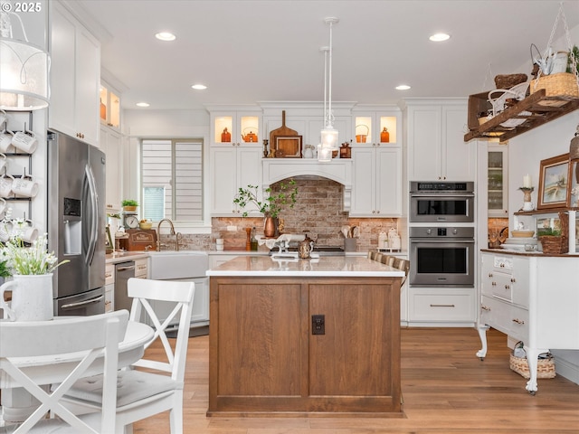 kitchen featuring decorative light fixtures, a center island, white cabinets, and appliances with stainless steel finishes