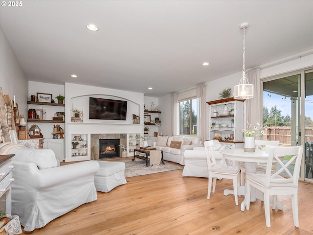 living room featuring a tiled fireplace and light hardwood / wood-style flooring