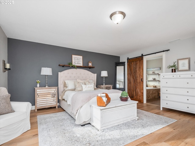 bedroom featuring a barn door and light wood-type flooring