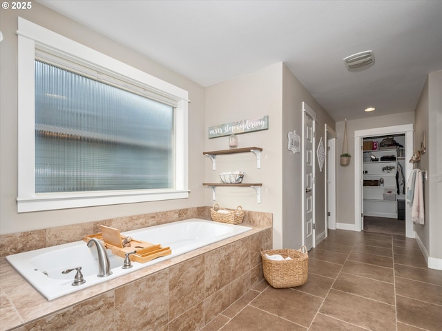 bathroom featuring a relaxing tiled tub and tile patterned flooring