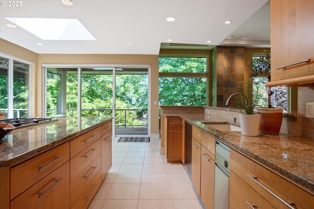 kitchen featuring a sink, a skylight, plenty of natural light, light tile patterned flooring, and recessed lighting