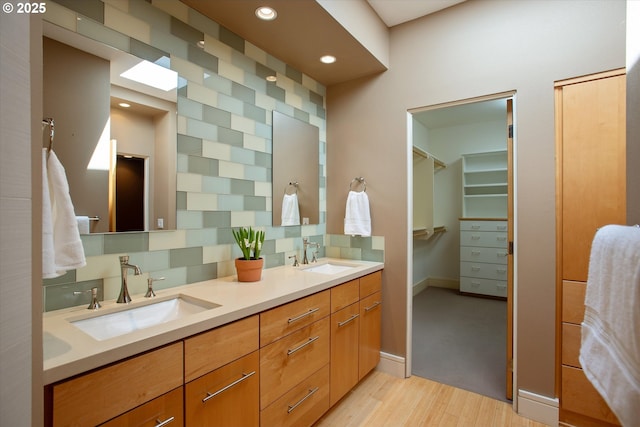 full bathroom featuring wood finished floors, double vanity, baseboards, recessed lighting, and a spacious closet