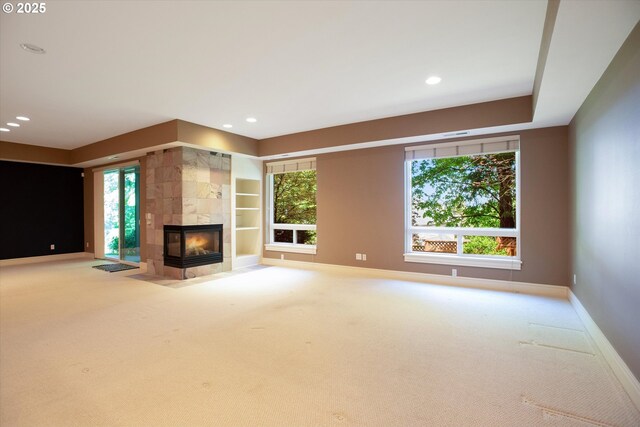 unfurnished living room featuring carpet flooring, baseboards, a fireplace, recessed lighting, and built in features
