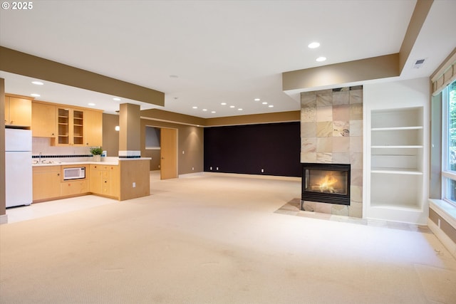 unfurnished living room with a sink, a fireplace, light carpet, recessed lighting, and built in shelves
