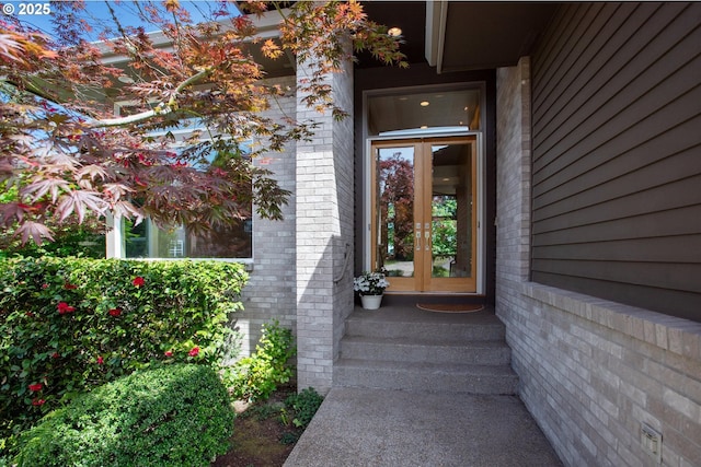 view of exterior entry featuring french doors and brick siding