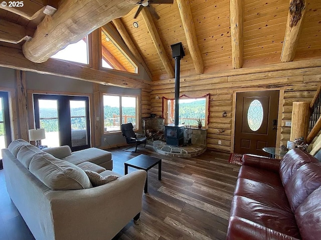 55778 SW Scoggins Valley Rd, Gaston, OR 97119 - living room with rustic walls, a wood stove, wooden ceiling with exposed beams, a ceiling fan, and dark wood-style floors