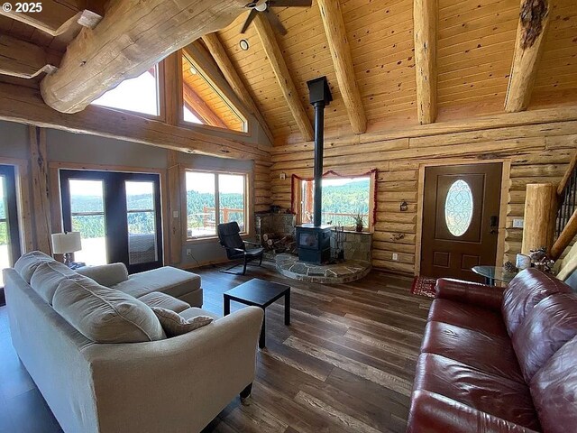 55778 SW Scoggins Valley Rd, Gaston, OR 97119 - living room with rustic walls, a wood stove, wooden ceiling with exposed beams, a ceiling fan, and dark wood-style floors