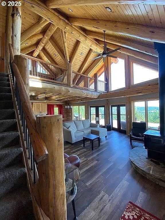 55778 SW Scoggins Valley Rd, Gaston, OR 97119 - living room featuring a wood stove, wooden ceiling with exposed beams, high vaulted ceiling, stairway, and hardwood / wood-style flooring