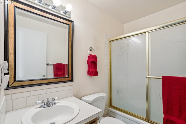 full bathroom with tasteful backsplash, vanity, shower / bath combination with glass door, and toilet